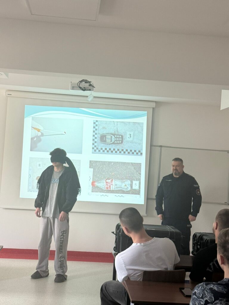 dwóch stojących  mężczyzn jeden z nich w opasce na oczach